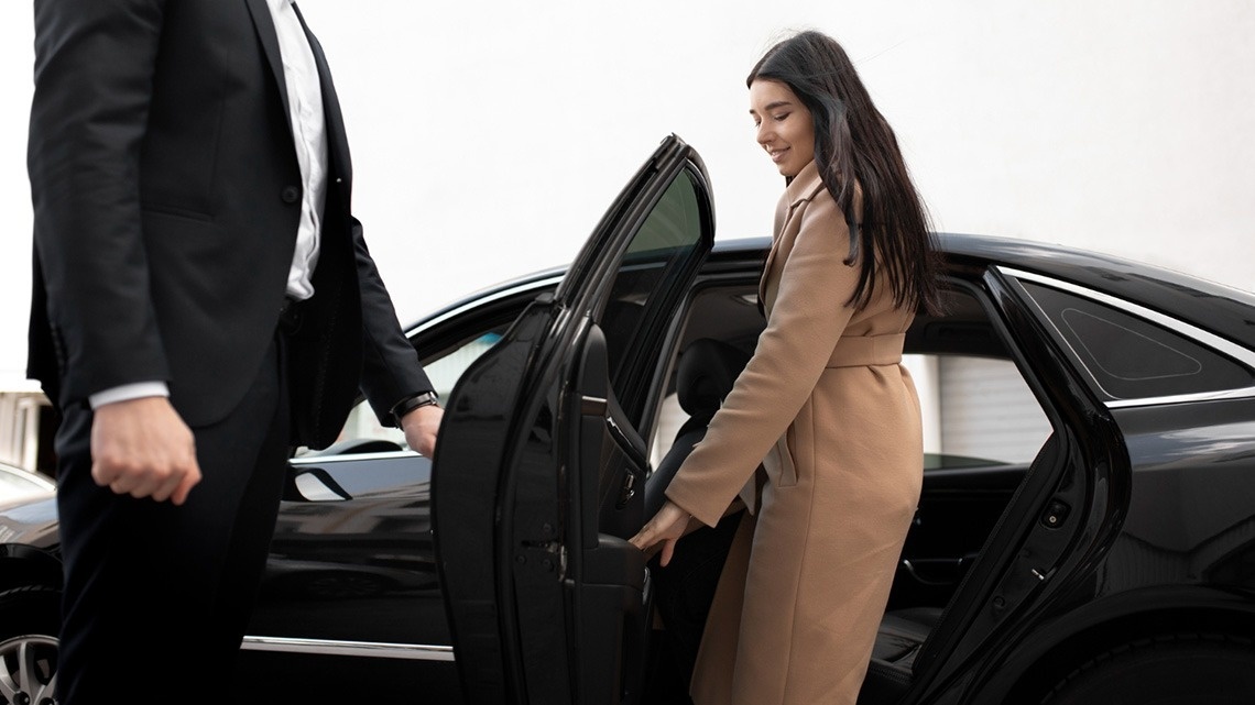 a woman in a tan coat is getting out of a car