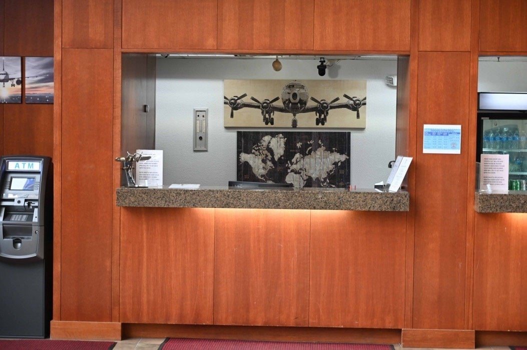 a painting of an airplane hangs above a counter in a hotel lobby