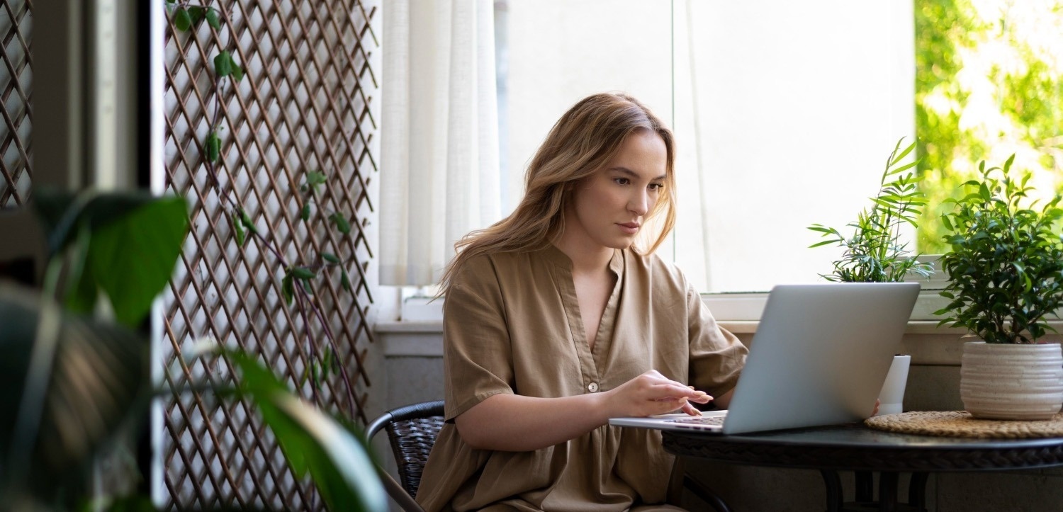 a woman sits at a table using a laptop computer