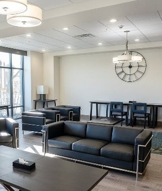 una sala de estar con sofás y sillas y un reloj en la pared