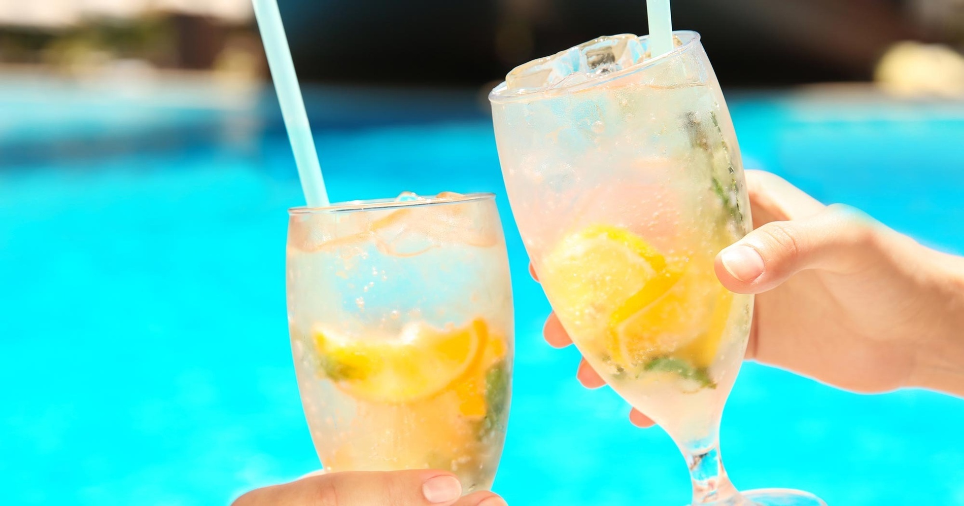 un plato de comida y un cóctel junto a una piscina