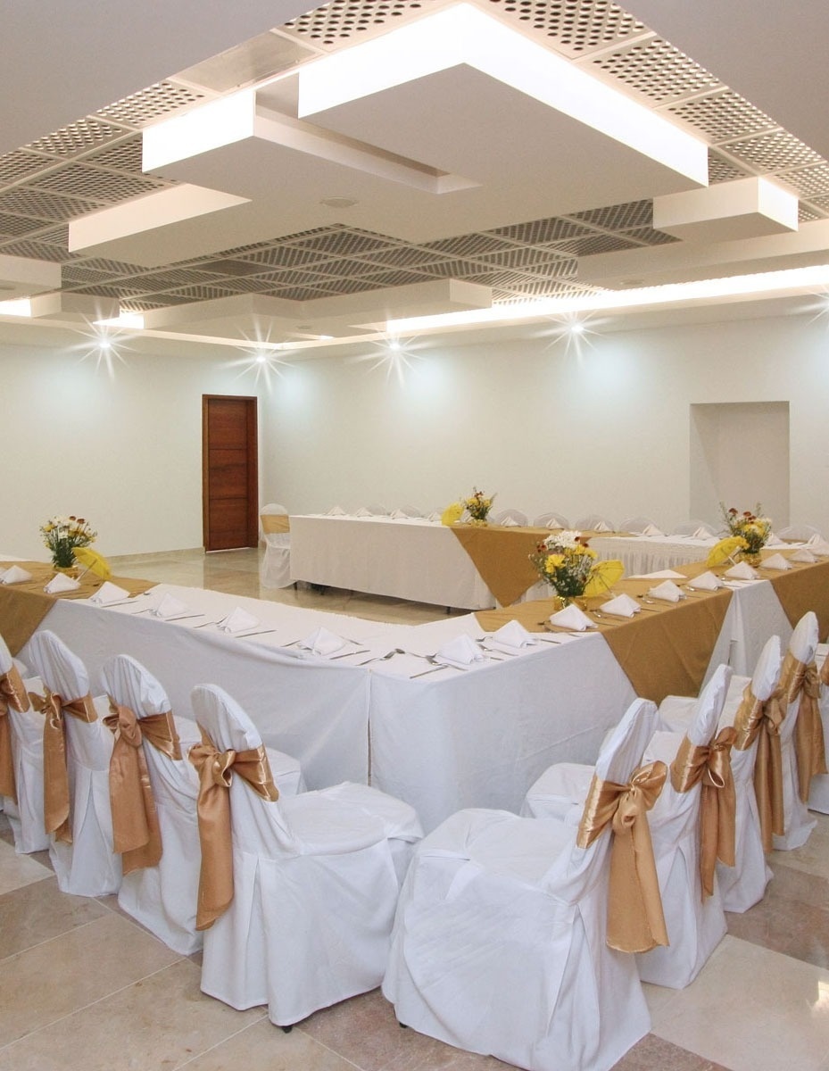 una sala de conferencias con mesas y sillas blancas y doradas