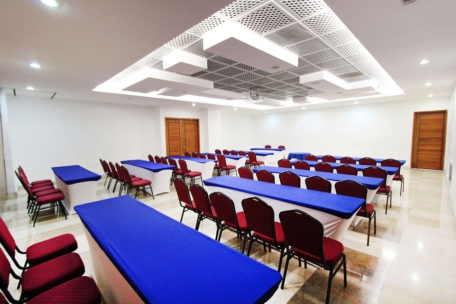 una sala de conferencias con mesas azules y sillas rojas