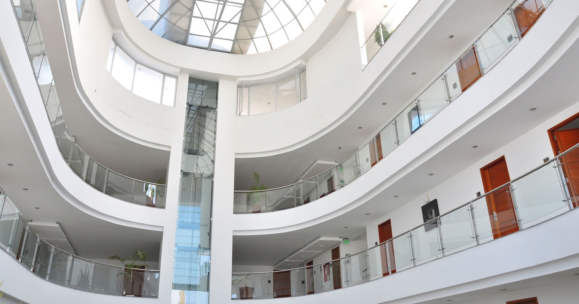 un gran edificio blanco con balcones de vidrio y puertas de madera