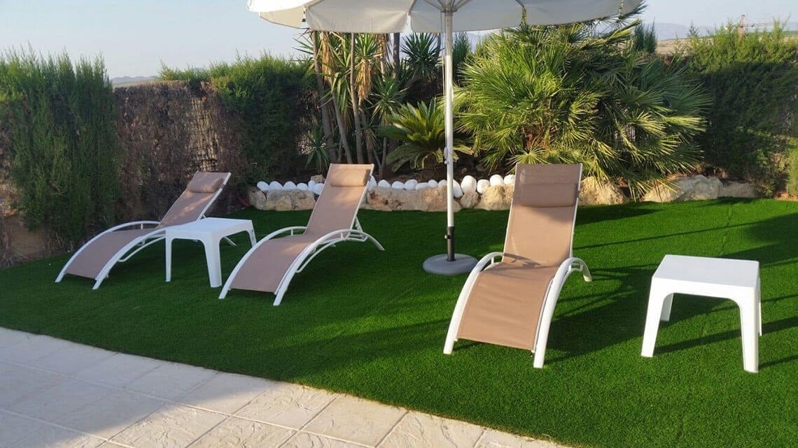 tres tumbonas y una mesa blanca en un patio