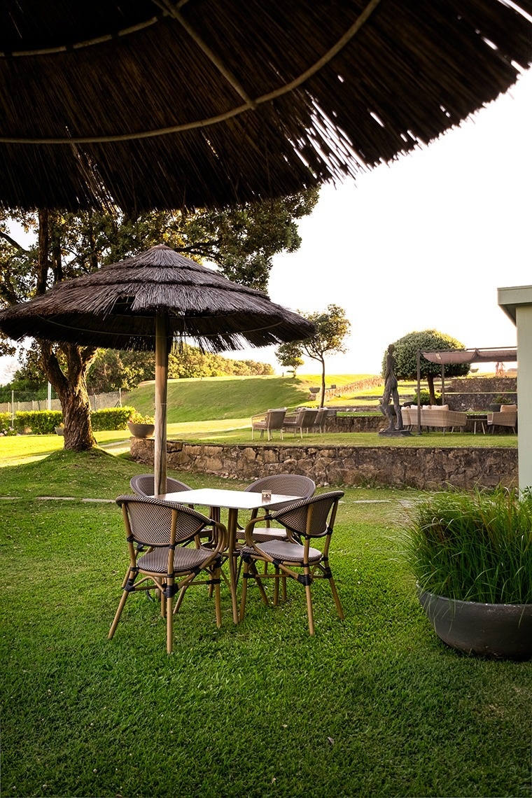 uma mesa e cadeiras sob um guarda-chuva de palha