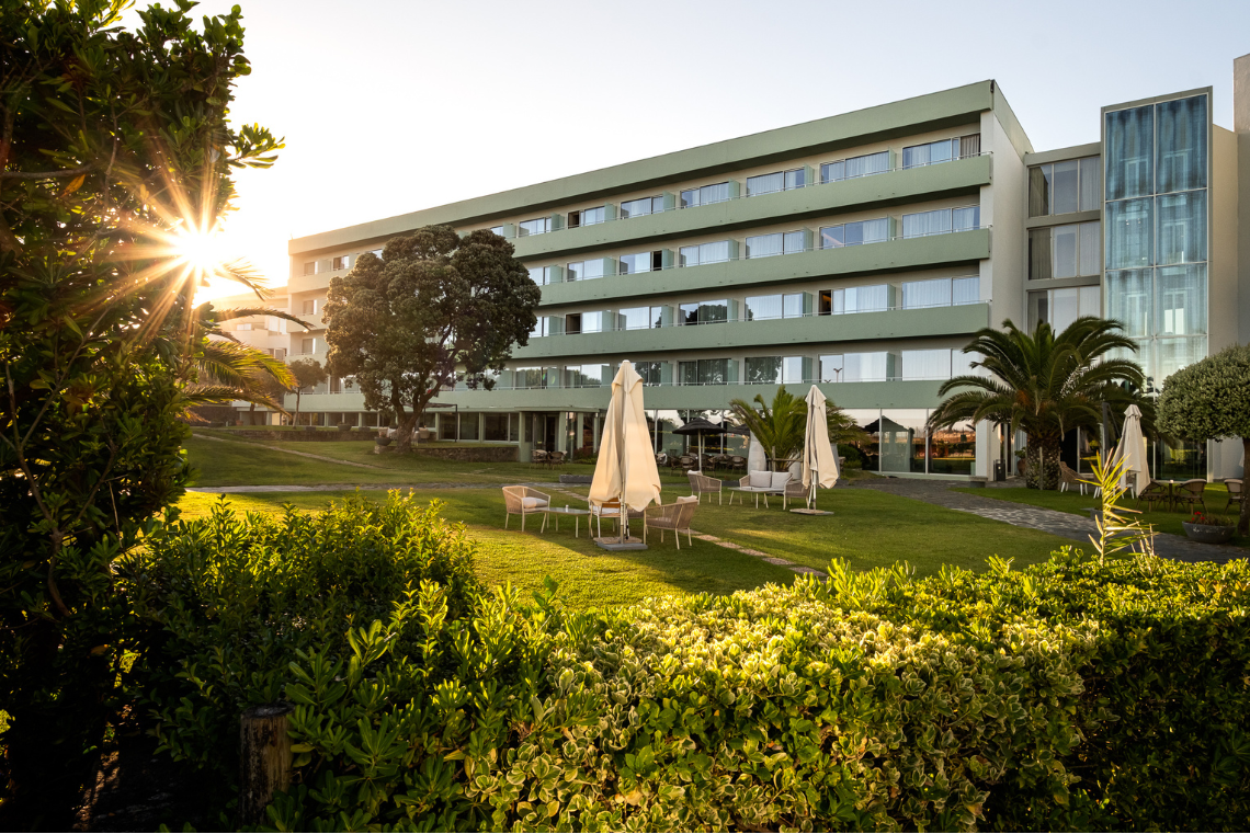 um grande prédio verde com muitas janelas e guarda-chuvas