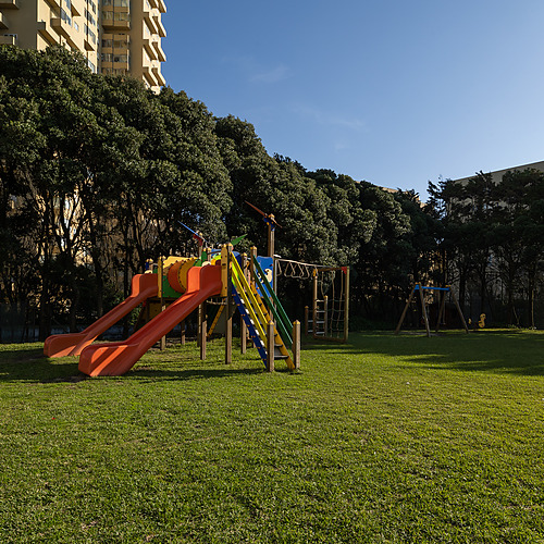 Parque infantil al aire libre enAxis: Corporate con toboganes y columpios junto a edificios residenciales.