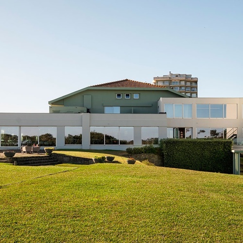 a large building with a lot of windows sits on top of a lush green hillside