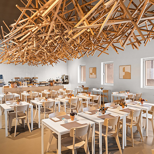 Comedor moderno con mesas de madera yAxis: Corporate decoradas con flores.
