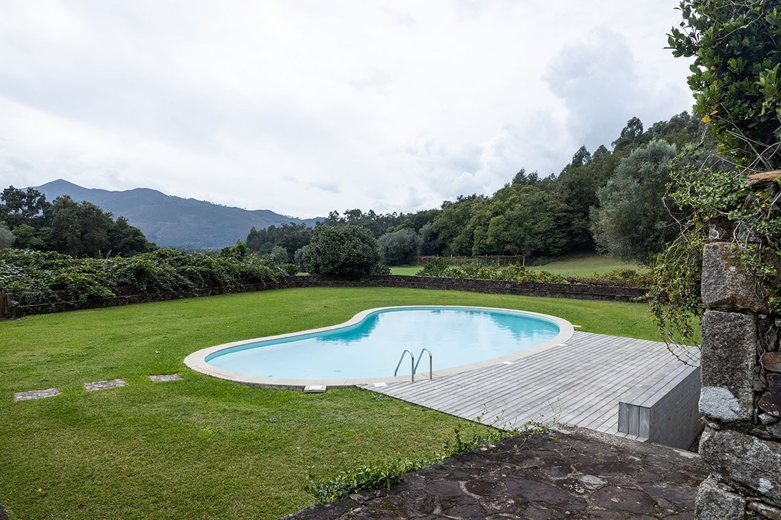 uma grande piscina com grama e montanhas ao fundo