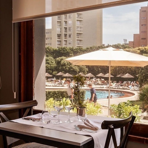 a restaurant table with a view of a pool and umbrellas