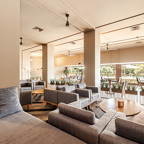 Salão de estar Axis: Corporate do hotel com sofás modernos, mesas de centro e vista para o jardim exterior.