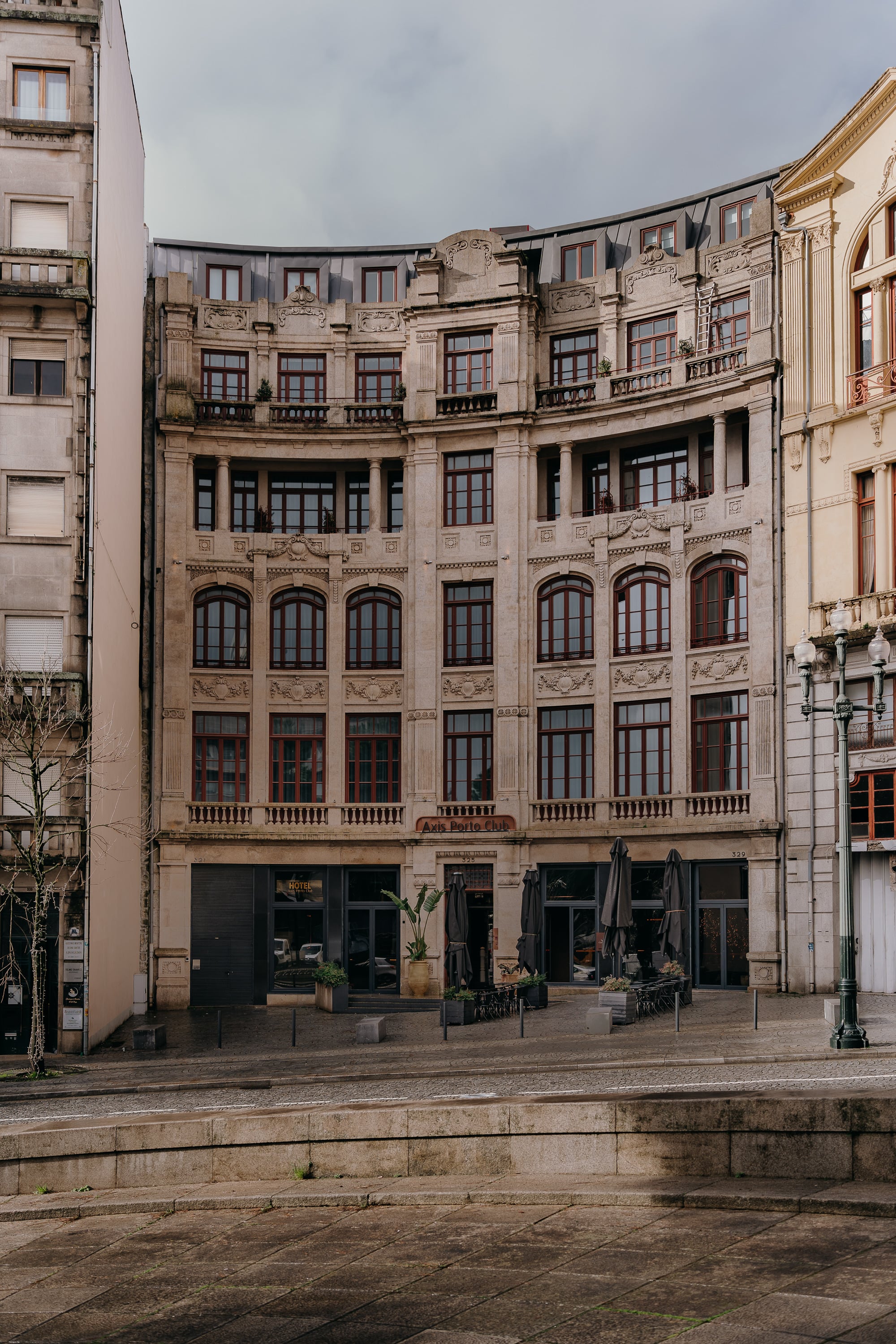 Hotel Porto Club | Axis Hotéis & Golfe | Website Oficial em arquitetura clássica com varandas e janelas em arco, em uma rua de paralelepípedos.