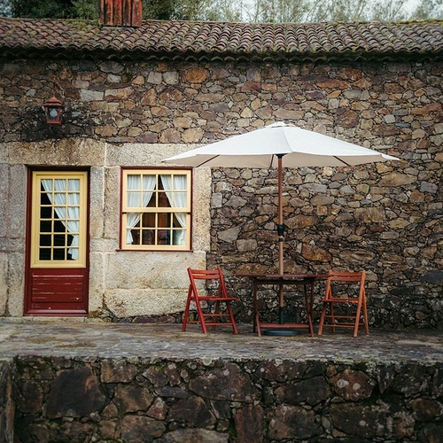 a stone building with a table and chairs under an umbrella