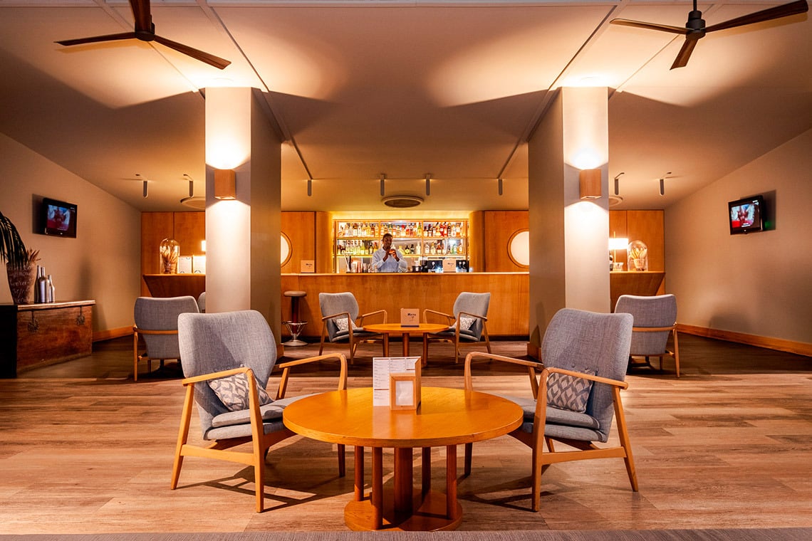 Lounge com assentos aconchegantes e bar ao fundo, ideal para relaxar no Vermar | Axis Hotéis & Golfe | Website Oficial.