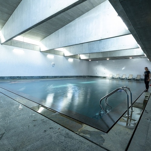 a large indoor swimming pool with a person standing on the edge