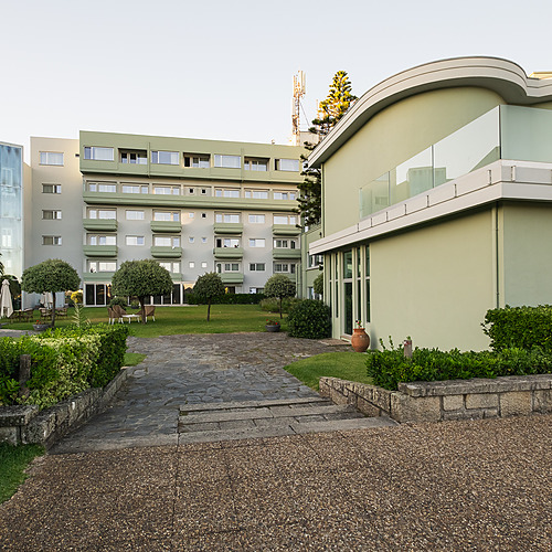Edificio moderno de hotel con piscina, césped y palmeras, ideal para tu Axis: Corporate.
