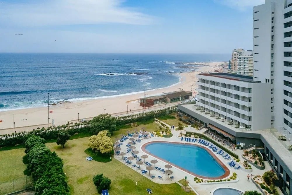 une grande piscine entourée d' un grand bâtiment avec une plage en arrière-plan