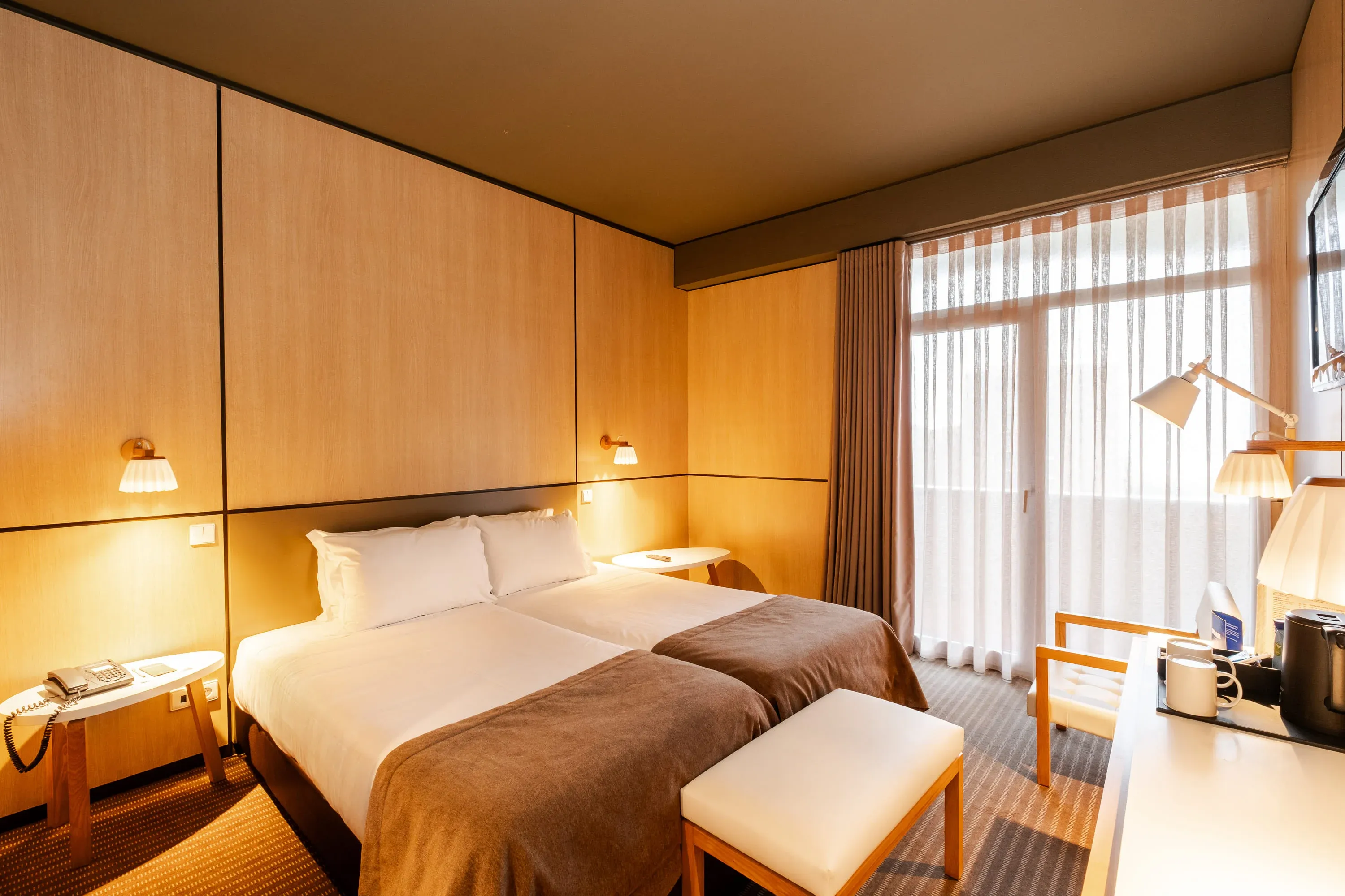 Quarto de hotel com duas camas,Vermar | Axis Hotéis & Golfe | Website Oficial, e janela com cortinas claras.