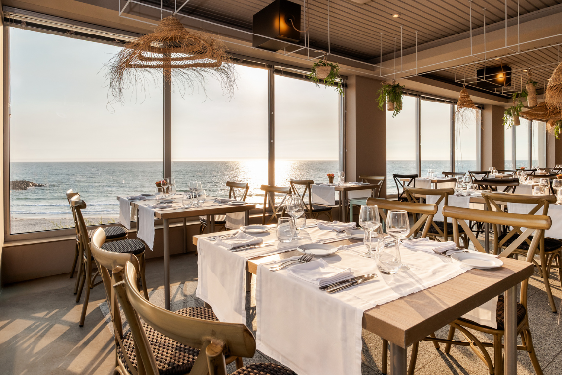 mesas e cadeiras em um restaurante com vista para o oceano