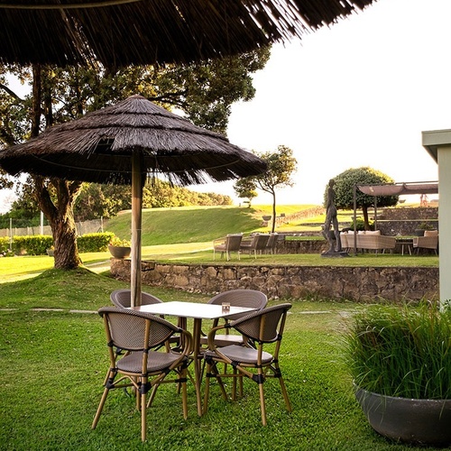 a table and chairs under a thatched umbrella