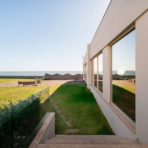 a white building with stairs leading up to a grassy area