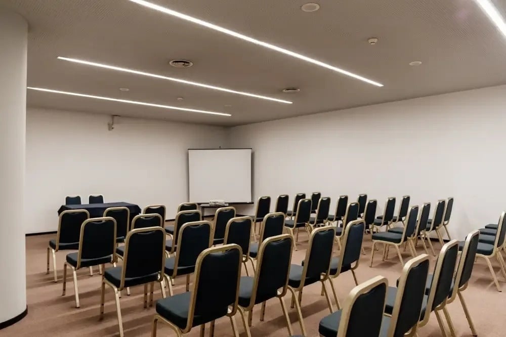 uma sala de conferências com cadeiras e uma tela de projeção