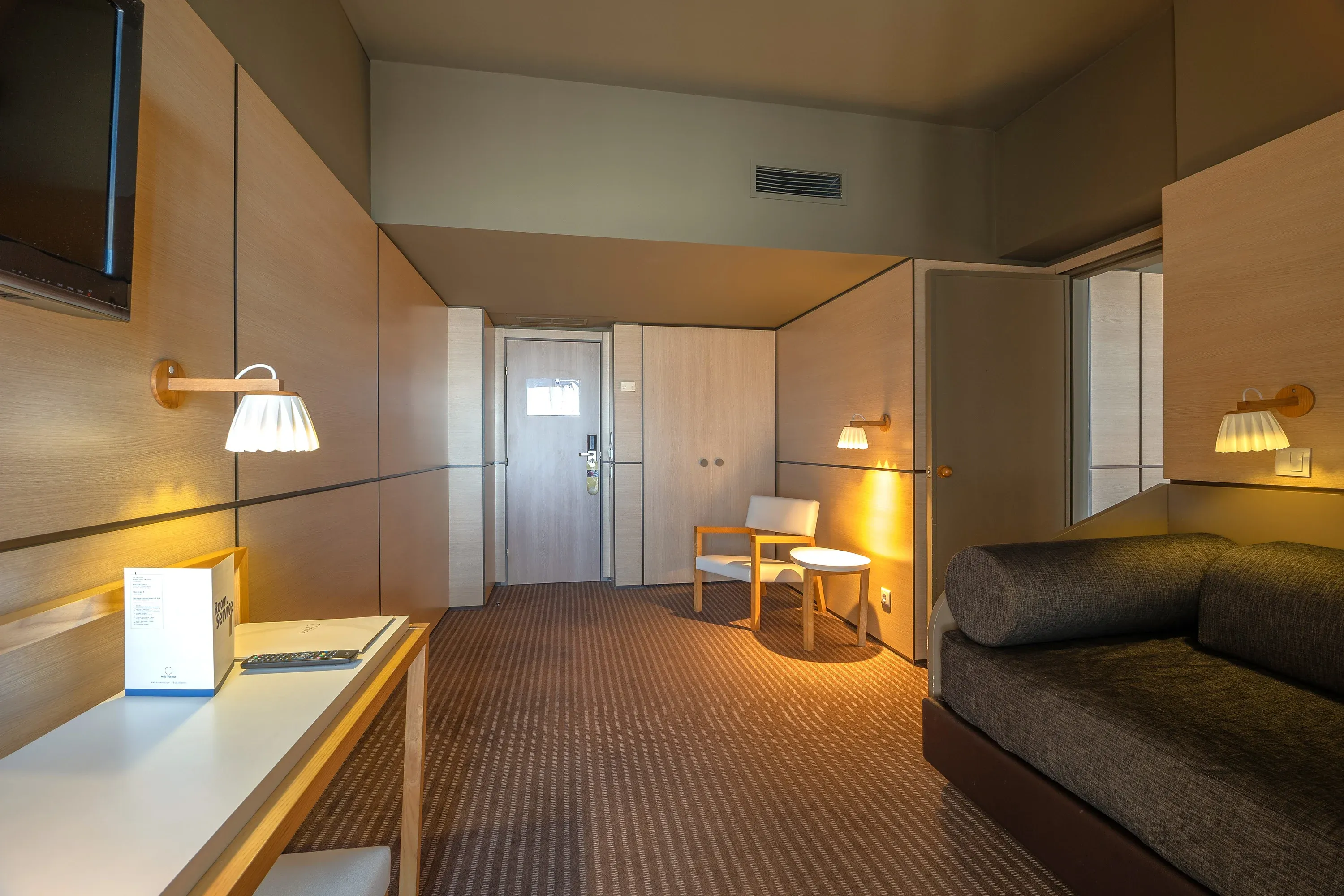 Quarto de hotel moderno com sofá, poltrona e mesa de serviço Vermar | Axis Hotéis & Golfe | Website Oficial.