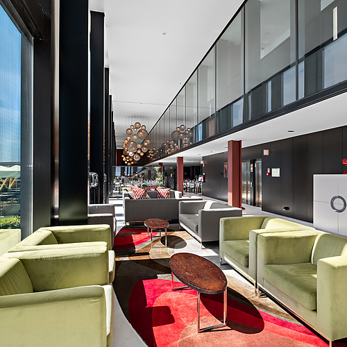 Lounge moderna com sofás verdes, mesas de centro e iluminação esférica. Axis: Corporate