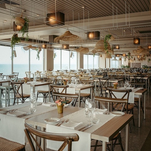 tables and chairs in a restaurant with a view of the ocean