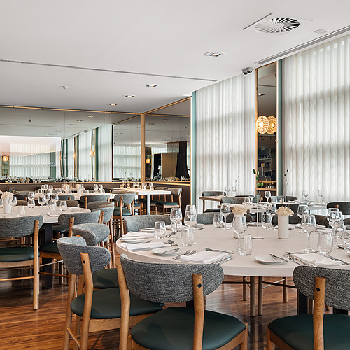 Mesas elegantes y sillas cómodas en un restaurante de hotel con decoración moderna y cortinas blancas. Axis: Corporate