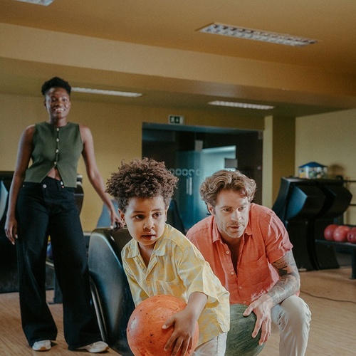 a man and a boy are bowling at a bowling alley