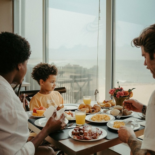 a family sitting at a table with plates of food and juice