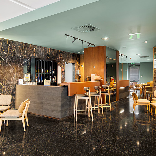 Bar y zona de asientos del hotel, con azulejos decorativos y 'Axis: Corporate' en el interior.
