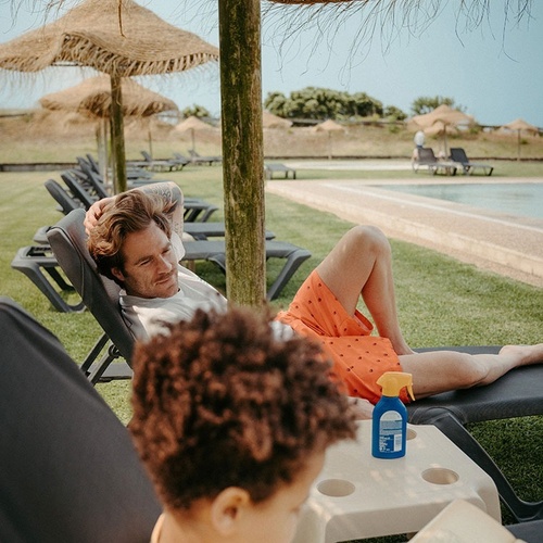 a man laying on a lounge chair next to a child reading a book