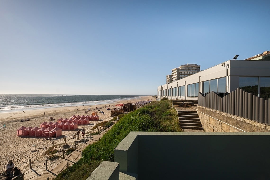 uma fileira de cabanas de praia rosa ao lado de uma praia