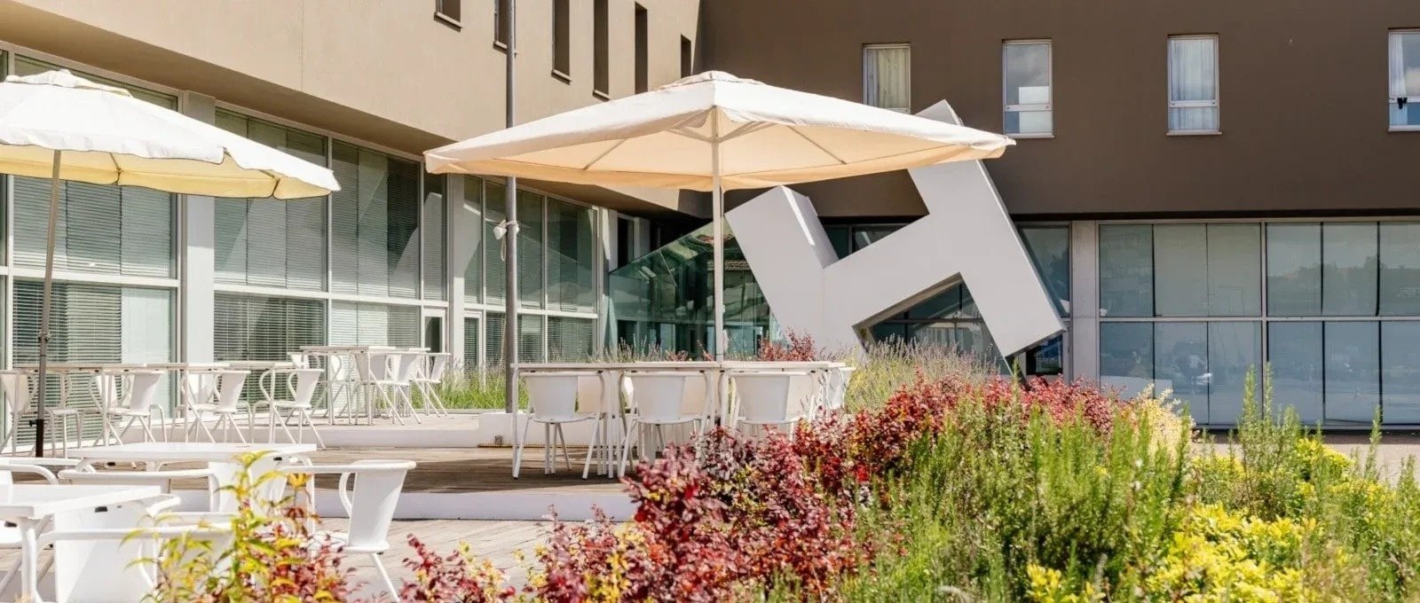 tables and chairs under umbrellas outside of a building