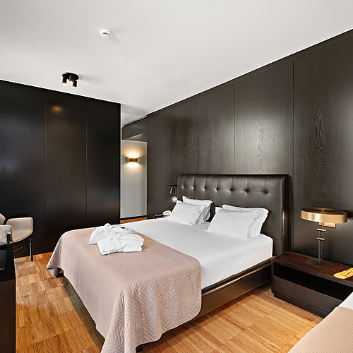 Quarto de hotel moderno com cama queen, roupão branco e vista para a janela com cortinas vermelhas. Axis: Corporate
