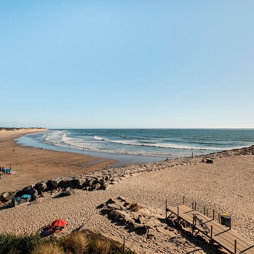 a beach with a wooden walkway leading to the ocean