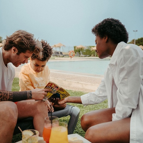 a boy wearing a shirt that says ' hawaii ' on it looks at a magazine