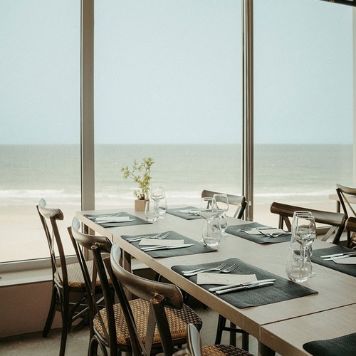 a restaurant with tables and chairs and a view of the ocean