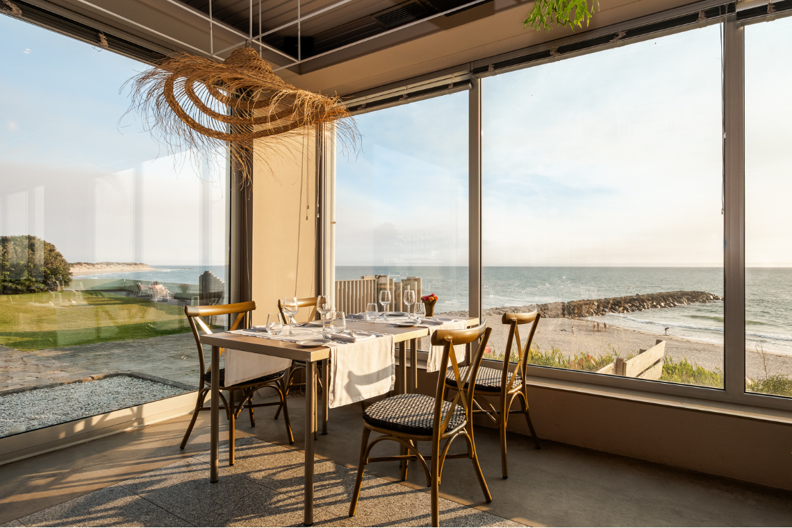 uma mesa e cadeiras em frente a uma janela com vista para o oceano