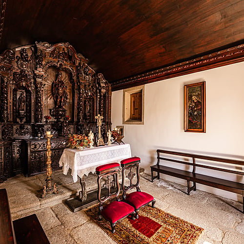 Interior de hotel: altar de madera ornamentado con alfombra, sillas y banco de madera. Axis: Corporate