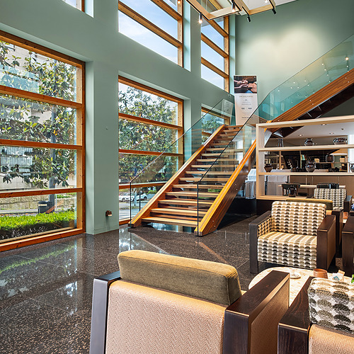 Axis: Corporate: sillones elegantes en un lobby moderno con escaleras de madera y cristal.