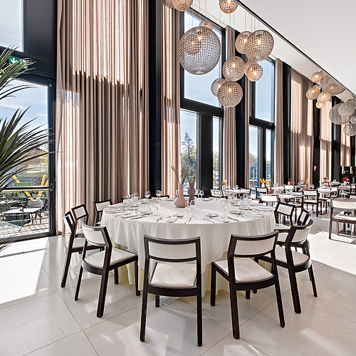 Jantar elegante em hotel com mesas postas, lustres e área externa. Perfeito paraAxis: Corporate.