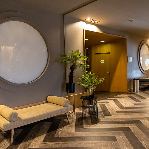 Lounge moderna com sofá, plantas e espelhos. Axis: Corporate.