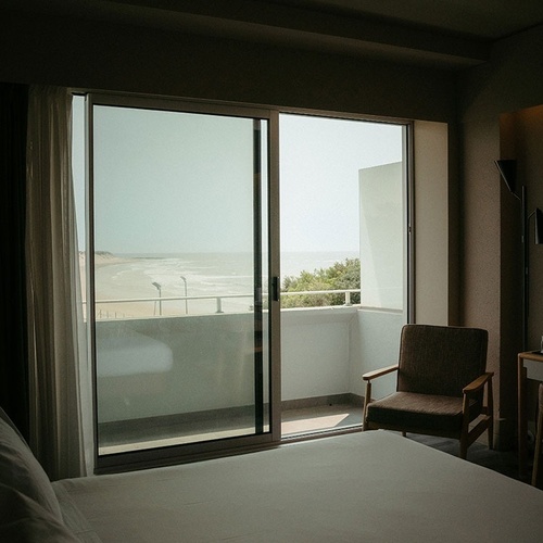 a bedroom with a sliding glass door leading to a balcony overlooking the ocean