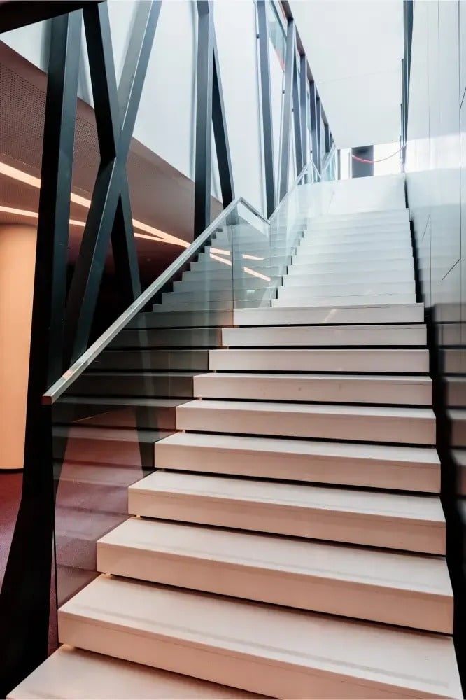 un escalier blanc dans un bâtiment avec un garde-corps en verre