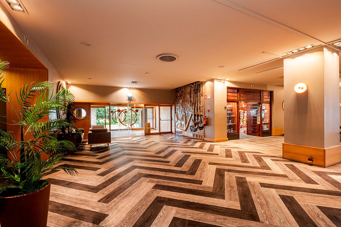 Hall de hotel com piso em espinha de peixe, plantas e recepção Vermar | Axis Hotéis & Golfe | Website Oficial.